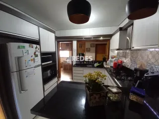Foto de uma cozinha moderna com armários brancos e bancadas escuras.