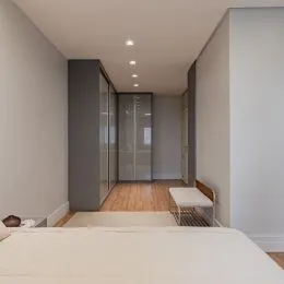 Quarto com armários embutidos e piso de madeira.