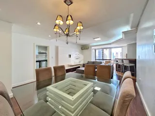 Sala de estar com piso de madeira e grandes janelas.