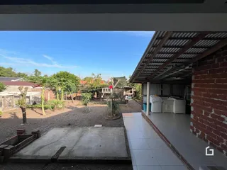 Vista externa de um quintal com área de concreto e muro de tijolos.