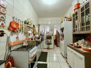 Uma cozinha com paredes de azulejo branco e armários brancos é visível na propriedade.