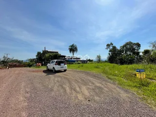 Uma estrada de terra leva a uma área com vegetação verde ao lado de uma propriedade.