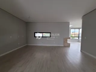 Ambiente interno de uma sala ampla com piso de madeira clara.