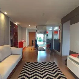 Foto interna de uma sala com piso de madeira e sofá.