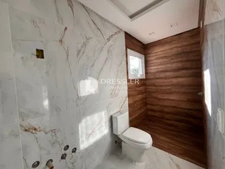 Foto de um banheiro com revestimento de mármore branco e parede de madeira.