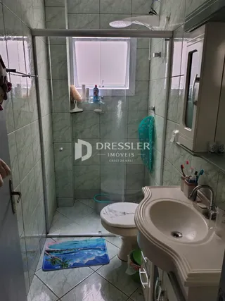 Foto de um banheiro com azulejos verdes e box de vidro.