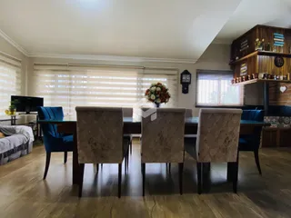 Uma sala de jantar com mesa de madeira e cadeiras em um ambiente claro.