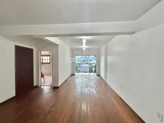 Corredor longo com piso de madeira e portas de entrada.
