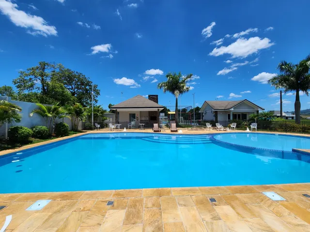 Piscina externa com deck e área verde em uma residência.