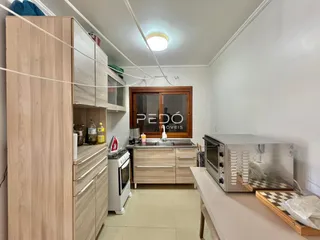 Cozinha com armários de madeira clara e paredes brancas.