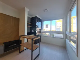 Ambiente interno com piso de madeira clara e grandes janelas.