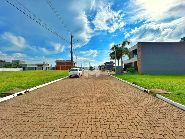Vista da entrada de uma propriedade em Lajeado, Brasil com gramado e estrada pavimentada.