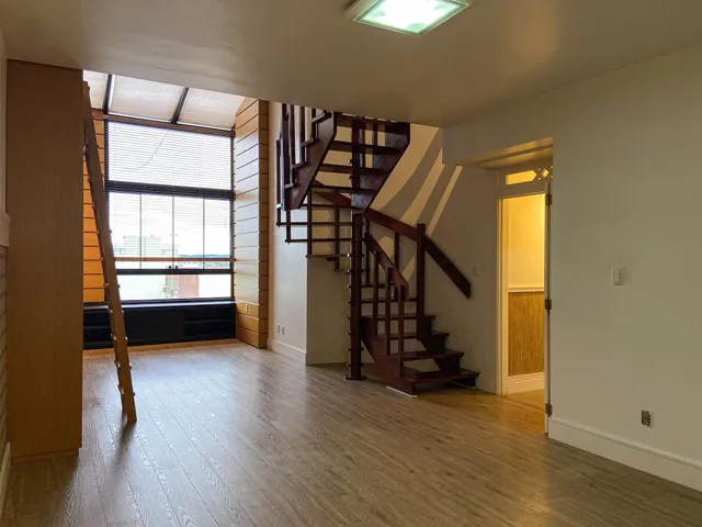 Foto de uma sala com piso de madeira e escadaria de madeira.