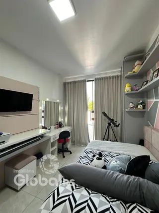 Quarto com cama e televisão em ambiente claro.
