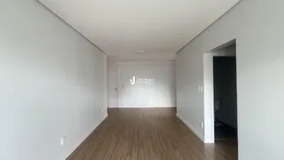 Corredor interno de uma residência com piso de madeira clara e paredes brancas.
