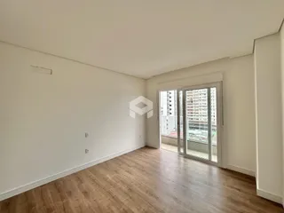 Ambiente interno de uma sala com piso de madeira clara e grandes portas de vidro.