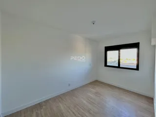 Parede branca e piso de madeira de um ambiente interno.