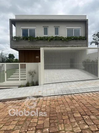 Fachada moderna de uma casa em Lajeado, Brasil com portão de ferro branco.