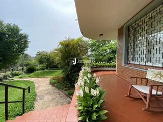 Vista da área externa com piso de tijolos vermelhos e jardim.