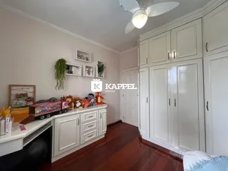 Quarto com armários brancos e piso de madeira escura.