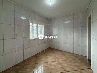 Foto de um cômodo interno com paredes brancas e piso de madeira clara.