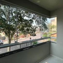 Vista externa de um apartamento mostrando árvores e área externa através de grandes janelas.