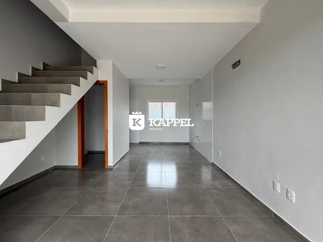 Hall de entrada com escadaria e piso de cerâmica em um imóvel.