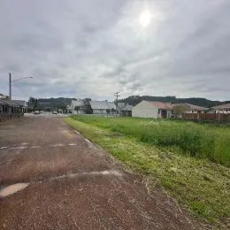 Vista externa de uma rua asfaltada com área gramada ao fundo.