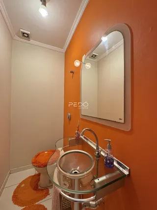 Foto de um banheiro com paredes laranjas e piso claro.