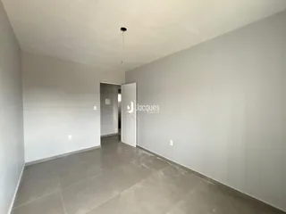 Hall de entrada com paredes brancas e piso de concreto.