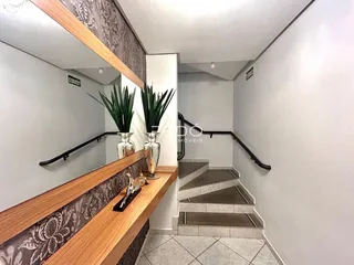 Hall de entrada com prateleira de madeira e escadaria em um imóvel no Brasil.