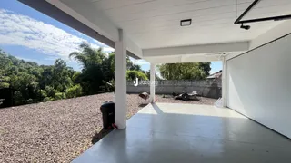 Vista externa de uma área de concreto com piso de cascalho e vegetação ao fundo.