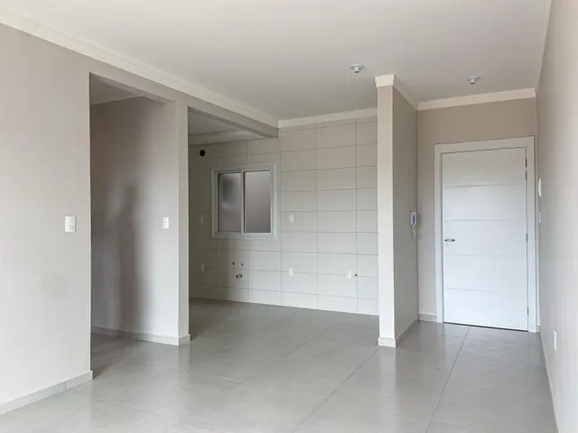 Um corredor interno com paredes brancas e piso claro.