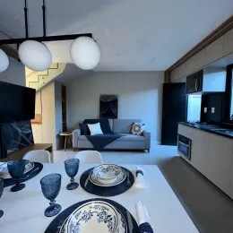 Uma mesa posta com louças e taças é visível na área de jantar.