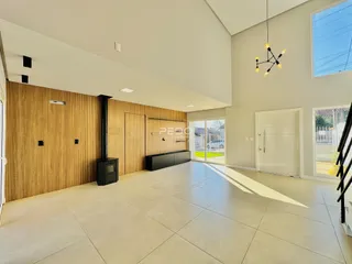 Uma sala de estar ampla com piso de cerâmica clara e paredes cinzas.