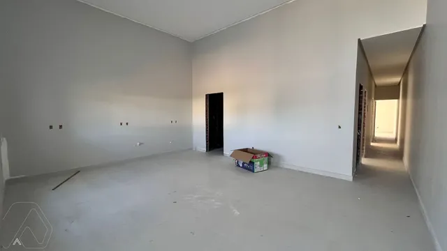 Foto de um cômodo amplo e vazio com paredes brancas e piso claro.