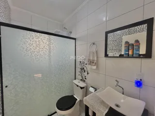 A foto mostra um banheiro com revestimento de azulejos brancos e box de vidro.