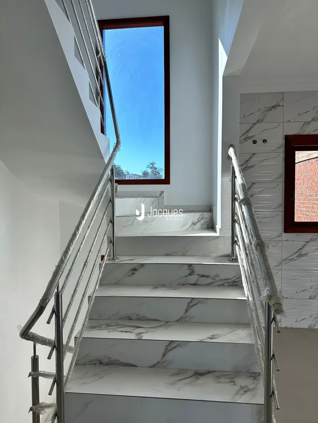Escadaria com degraus de mármore branco e parede branca em um imóvel.