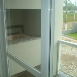 Vista interna de um cômodo com paredes brancas e molduras brancas.