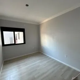 Ambiente interno com paredes cinzas e piso de madeira clara.