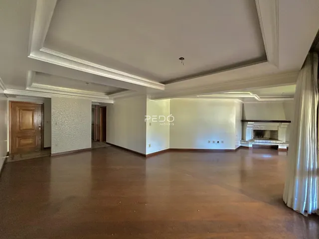 Sala ampla com piso de madeira e molduras de teto.