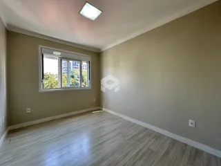 Sala de estar com piso de madeira clara e grande janela.