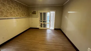 Foto interna de uma sala com piso de madeira e papel de parede.