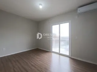 Ambiente interno de uma sala com piso de madeira clara e porta de vidro.
