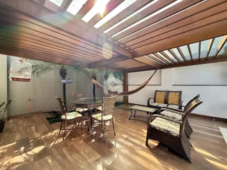 Ambiente interno com teto inclinado de madeira e mobiliário de vime.