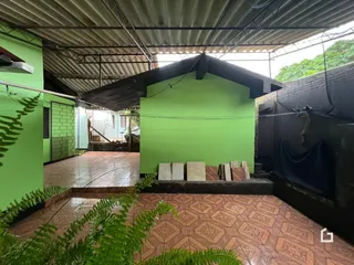 Uma área externa com piso de cerâmica e paredes verdes.