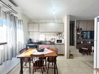 Foto de uma sala de jantar com mesa de madeira e armários na cozinha.