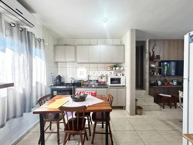 Foto de uma sala de jantar com mesa de madeira e armários na cozinha.
