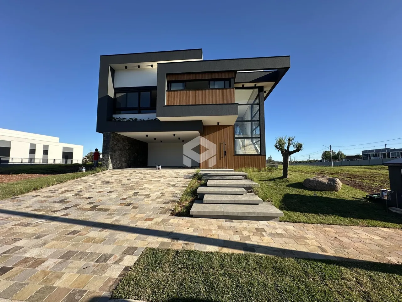 Fachada moderna de uma residência em Lajeado, Brasil, com área externa pavimentada.