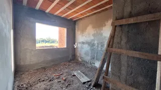 Foto de um cômodo interno com paredes de concreto aparente e piso de terra.